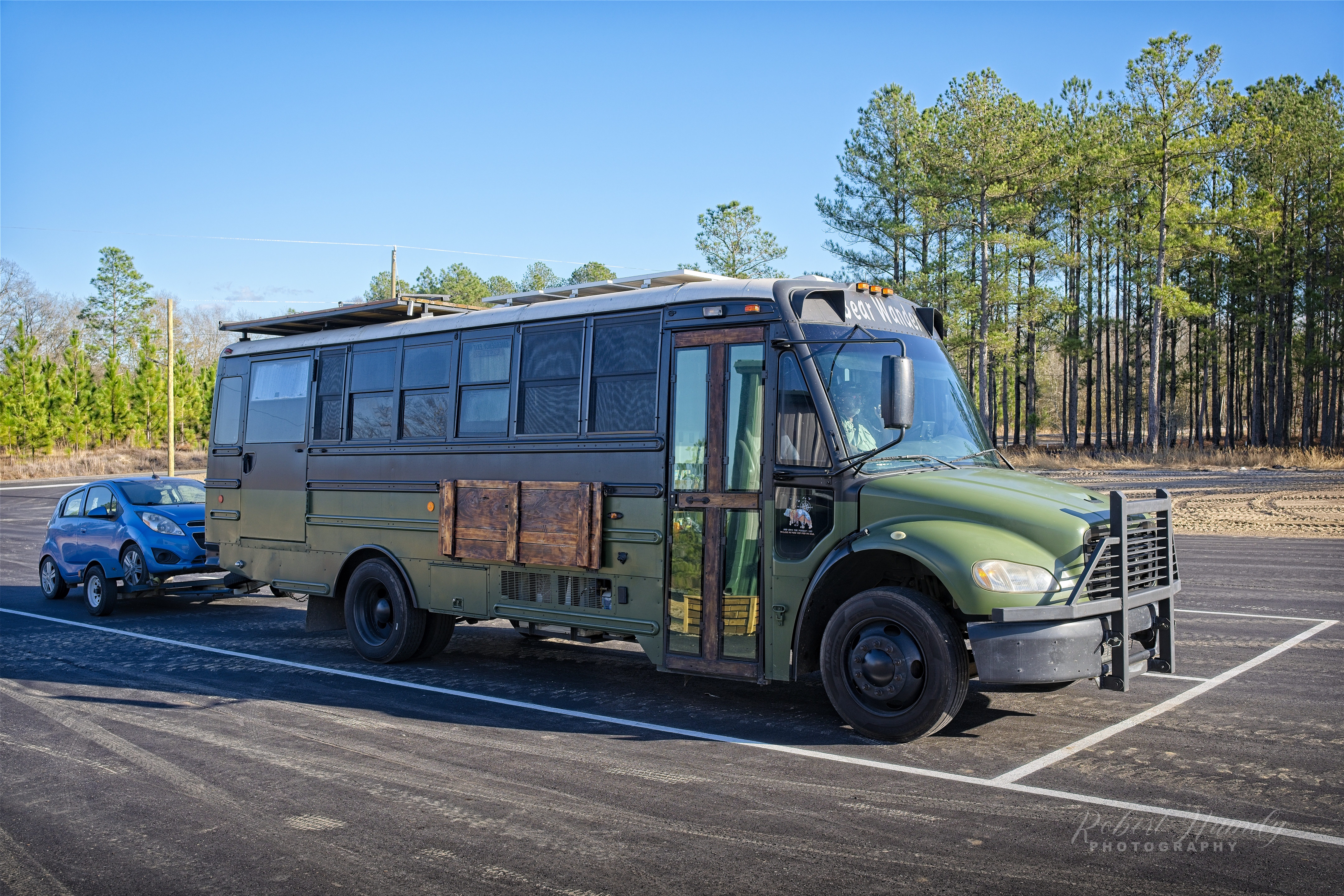 A colorful RV checking in at Standing Pines Campground on a sunny day, surrounded by natural beauty